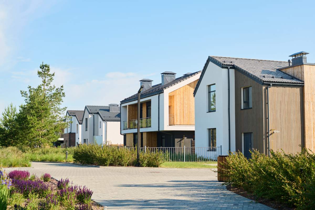 Perspective view of modern two storey village houses with small front yards surrounded by fence and green vegetation