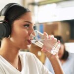 Shot of a young businesswoman drinking a glass of water at work.