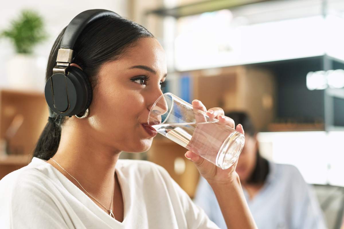 Shot of a young businesswoman drinking a glass of water at work.