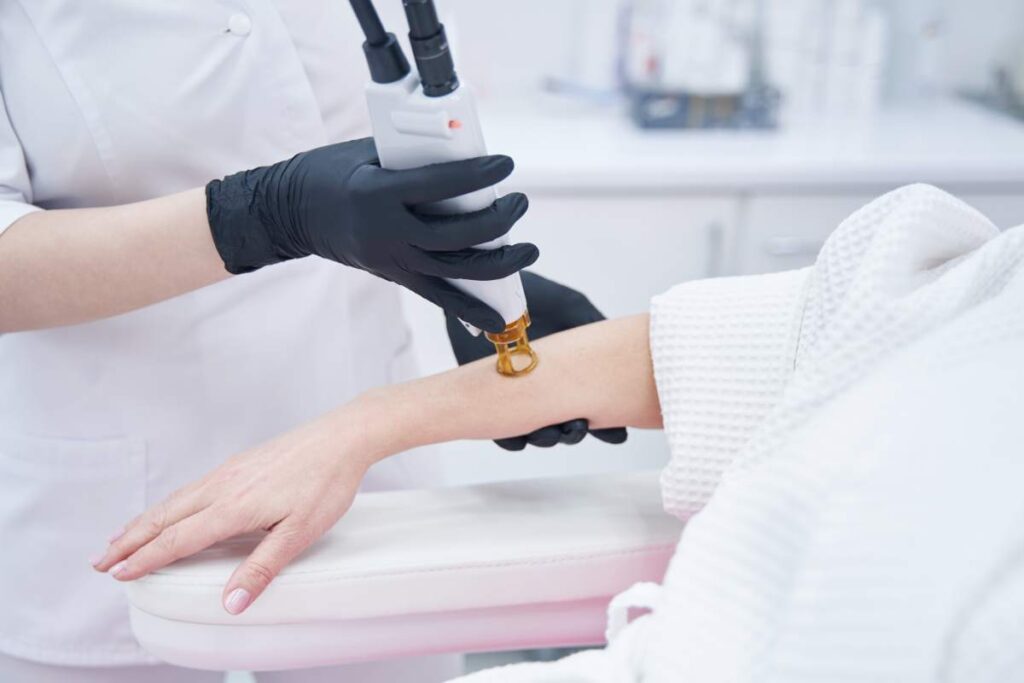 Close up of female doctor hands in sterile gloves removing hair from woman arm with alexandrite laser machine