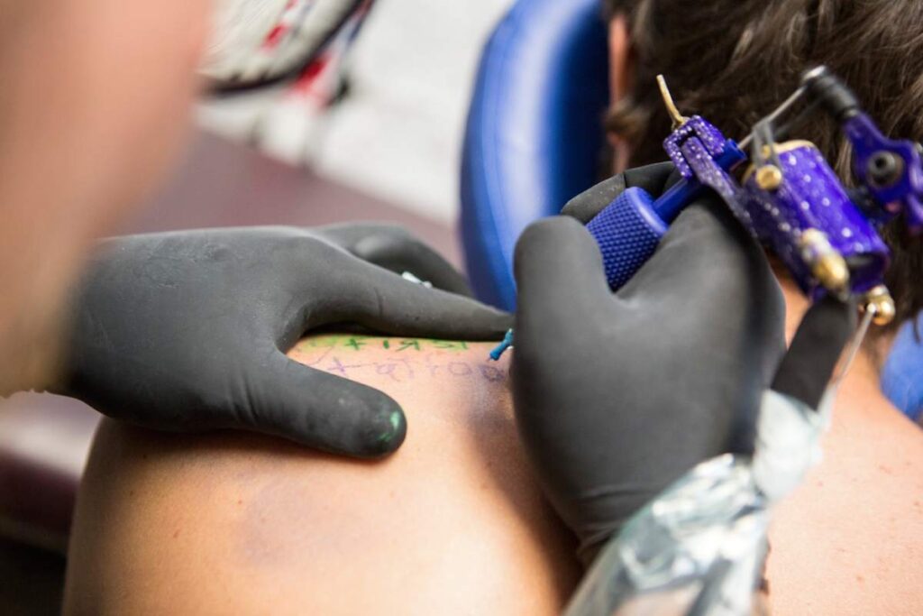 Close up of tattooist giving customer their first tattoo