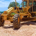 Heavy an earthmoving construction grader tractor with working at construction site