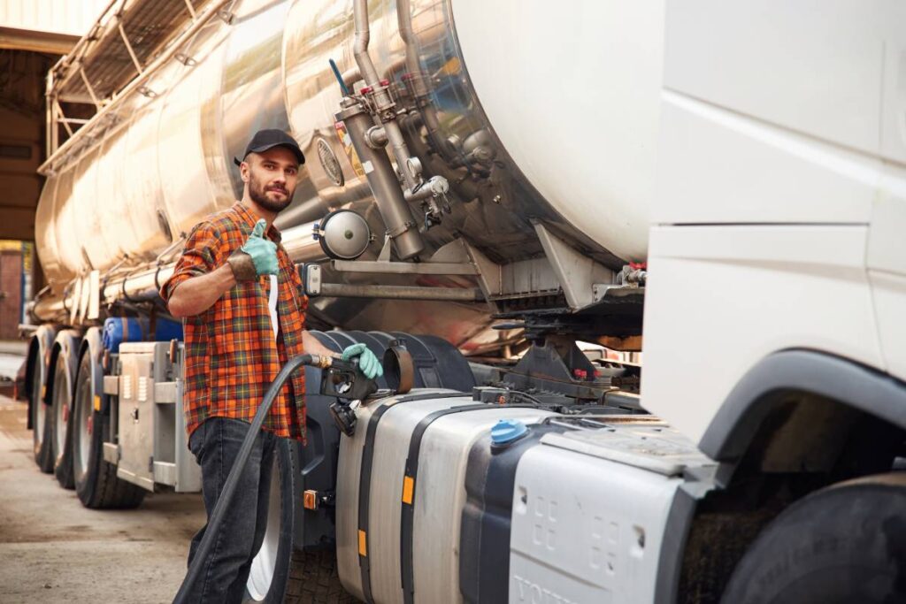 Holding refueling device. Young truck driver in casual clothes.