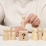 Woman keeps the red wooden figurine separate from the group. Career growth concept, unique person.