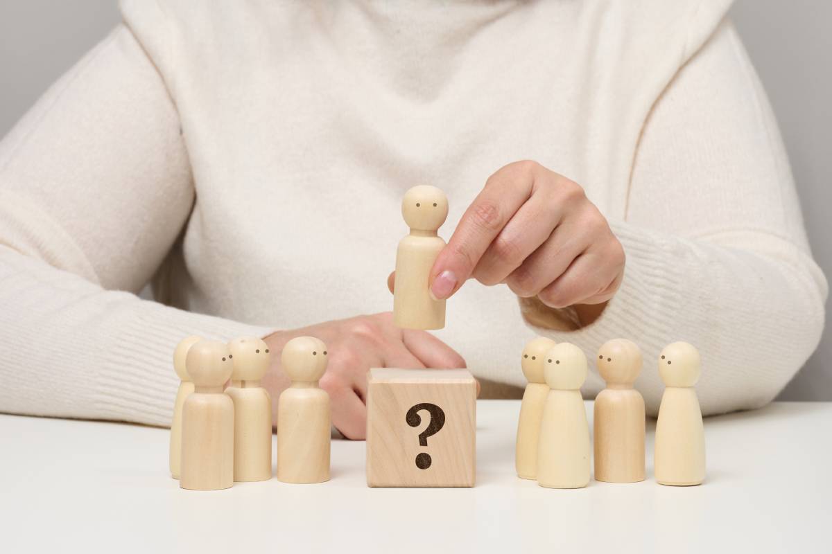 Woman keeps the red wooden figurine separate from the group. Career growth concept, unique person.