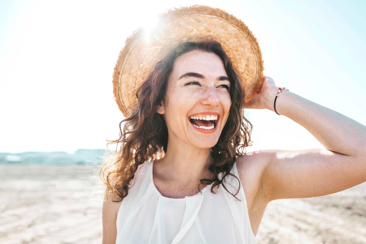 Happy beautiful young woman smiling at the beach side - Delightful girl enjoying sunny day out - Healthy lifestyle concept with female laughing outside